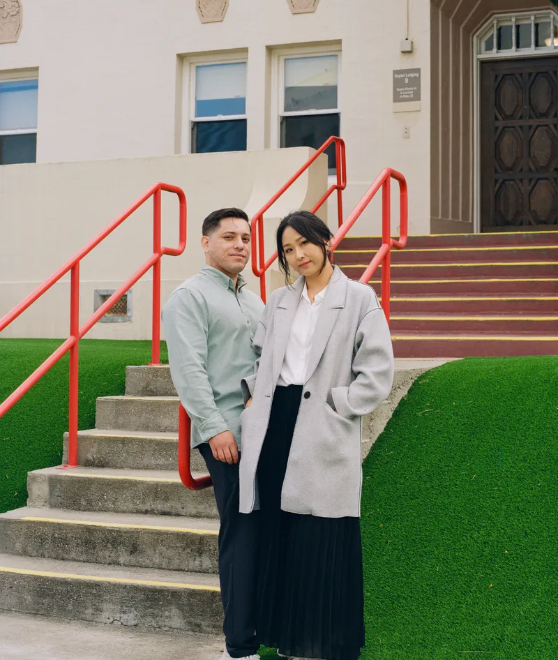 Eden and Luis standing together on steps with red railings