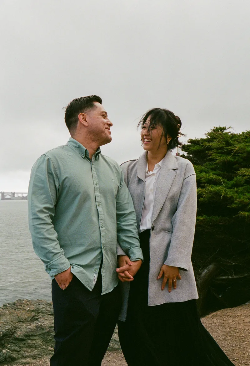 Eden and Luis holding hands and laughing by the bay