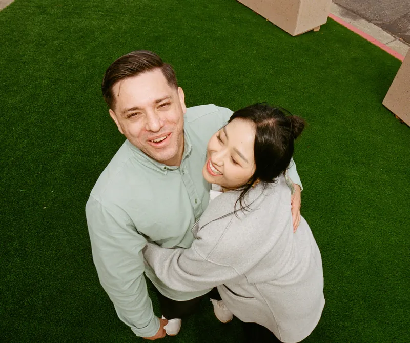 Eden and Luis hugging, photographed from above on green turf