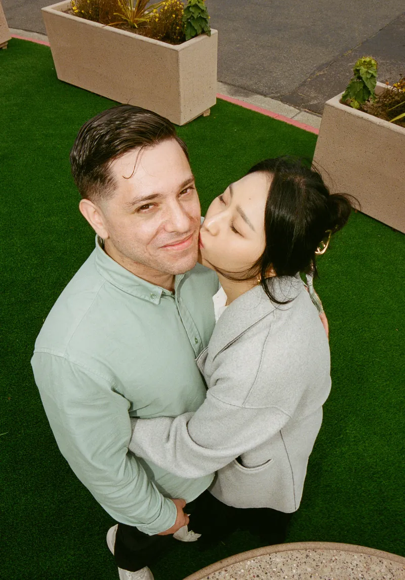 Eden kissing Luis on the cheek as they hug on green turf